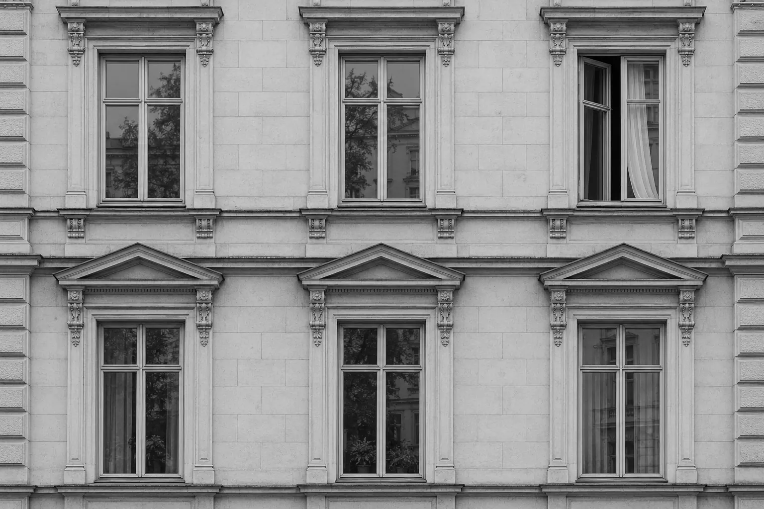 Fassade eines Altbaus im Lehel mit sechs hohen Fenstern in zwei Reihen, ein Fenster ist geöffnet.